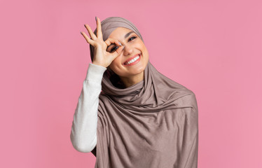 Happy islamic girl showing ok sign with hand on eye