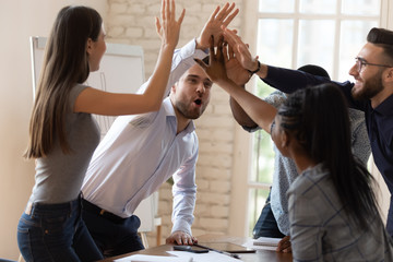 Overjoyed diverse employees give high five celebrating success