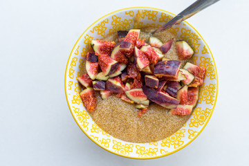Gluten free amaranth porridge for breakfast with figs in a yellow bowl top view