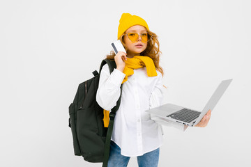 student girl in casual clothes with a backpack on her shoulders and with a laptop in her hands walking and reading the news on a white background
