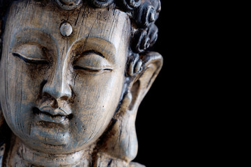 Fototapeta na wymiar Kopf einer hölzernen Buddha-Skulptur isoliert auf schwarzem Hintergrund mit Platz für Text