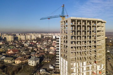 Aerial view of concrete frame of tall apartment building under construction in a city.