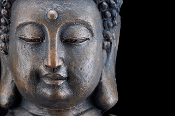 Fototapeta na wymiar Porträt des Kopfes einer Buddha-Figur aus Bronze freigestellt auf schwarzem Hintergrund mit Platz für Text