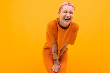 girl with pink hair and a pierced face dressed in a loose orange dress on a yellow background