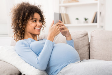 African-american pregnant woman browsing on smartphone, free space