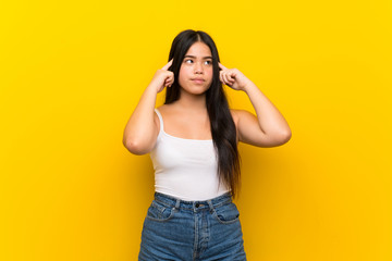 Fototapeta premium Young teenager Asian girl over isolated yellow background having doubts and thinking
