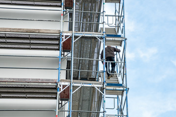 Bauarbeiter der auf einem Gerüst die Treppe nach oben geht