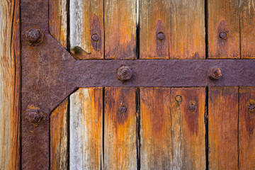 Detail of a large wooden gate with rusted iron fittings.