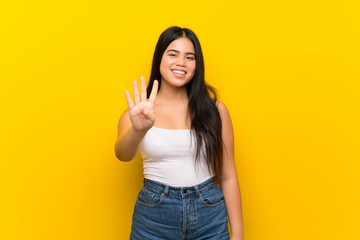 Young teenager Asian girl over isolated yellow background happy and counting four with fingers