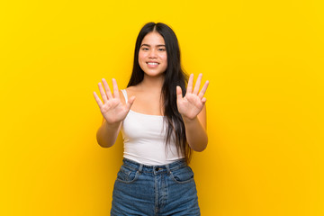 Young teenager Asian girl over isolated yellow background counting nine with fingers