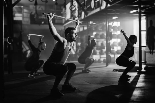 Black and white photo of athletic people having cross training in a gym.