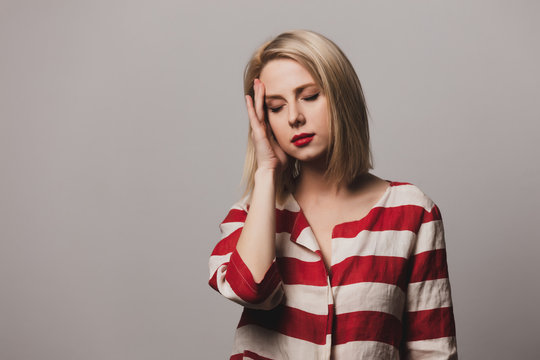 beautiful blonde woman in striped jacket hold head
