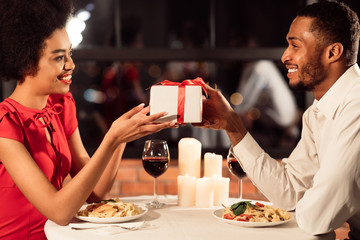 Guy Giving Valentine's Present To Girlfriend During Date In Restaurant