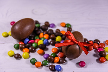 Chocolate easter eggs and multicolored candies on wooden table