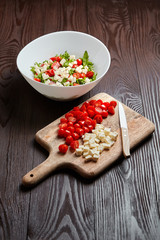 Cherry tomatoes with salad cheese on cutting board on wooden table. Cooking vegetable salad