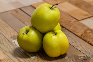 Close-up shot using a 105mm macro lens featuring stacked green apples on a rough wooden top shot using a shallow depth of field