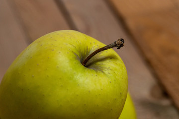 Close-up macro shot using a 105mm macro lens focussing on the top of the green apple in the shot using a shallow depth of field and havind a wooden background