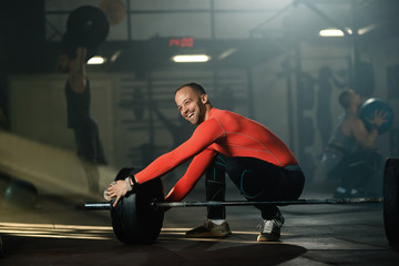 Obraz na płótnie Canvas Happy sportsman preparing barbell for weight training in a gym.