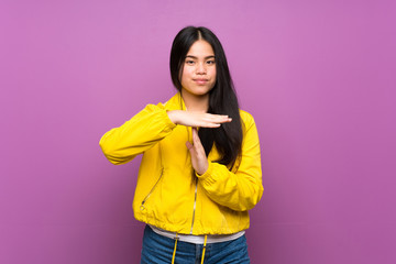 Young teenager Asian girl over isolated purple background making time out gesture