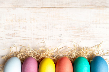 Easter concept. Colorful eggs on white wooden background with copy space for text. Top down view or flat lay