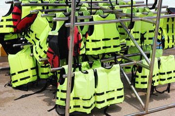 A lot of bright yellow life jackets hanging on the beach. The concept of water safety.
