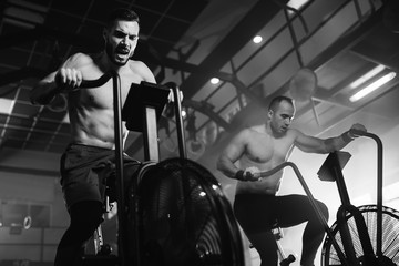 Below view of determined men working out on exercise bikes in a gym.