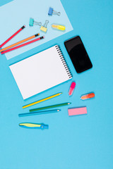 Mobile phone and different stationery isolated on whitte and blue background