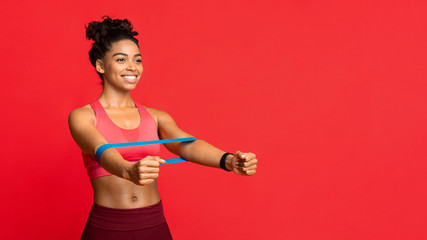 Happy afro girl doing stretching work out with elastic bands