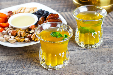 Oriental tea with mint, honey, nuts and dried fruits on wooden table background. Ramadan drink