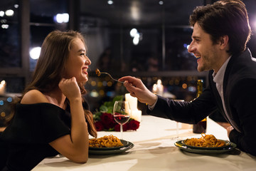 Cheerful man feeding his girlfriend on romantic date