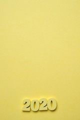 Figures from wood 2020 in the right corner on a yellow background. Concept of the year. Top view. Copy space. Vertical.