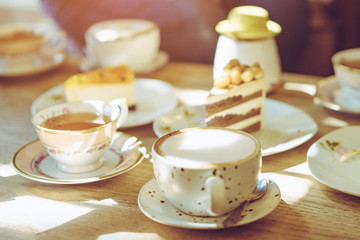 Happiness female friends meeting and drinking tea or coffee with cakes together at cafe in the afternoon. People, leisure and communication concept. Selective focus.
