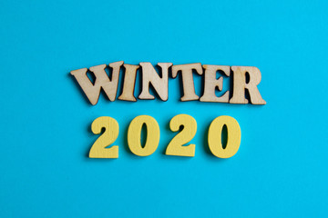 The concept of winter in the new year. Wooden numbers 2020 with letters on a blue background. Top view.