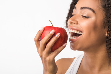 Cheerful black girl biting apple with free space