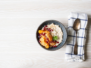 Oatmeal with fresh tangerine slices and pomegranate seeds, ground almonds and mint in a blue bowl on white background. Copy space. Top view