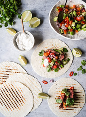 Tortillas with vegetables and beef steak slices. Avocados, tomatoes, red onions and meet with cilantro and lime juice in tortillas. Mexican food.