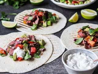 Tortillas with vegetables and beef steak slices. Avocados, tomatoes, red onions and meet with cilantro and lime juice in tortillas. Mexican food.