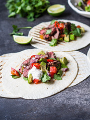 Tortillas with vegetables and beef steak slices. Avocados, tomatoes, red onions and meet with cilantro and lime juice in tortillas. Mexican food.