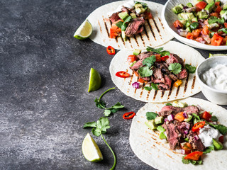 Tortillas with vegetables and beef steak slices. Avocados, tomatoes, red onions and meet with cilantro and lime juice in tortillas. Mexican food. Copy space