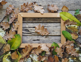 Autumn composition on an ancient wooden background with autumn leaves and a frame for an inscription or photo. Art photo.