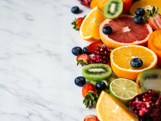 Fototapeta na wymiar Multicolored seasonal healthy natural fruit composition with persimmon, blueberries, orange, kiwi, strawberries, grapefruit, pomegranate, orange slices. Copy space