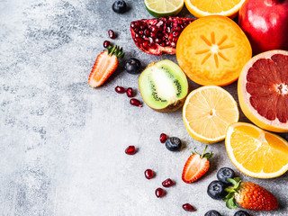 Multicolored seasonal healthy natural fruit composition with persimmon, blueberries, orange, kiwi, strawberries, grapefruit, pomegranate, orange slices. Copy space