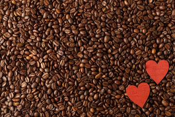 Dark background of coffee beans with red hearts. Top view