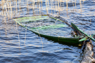 a green rowing boat sank in the water