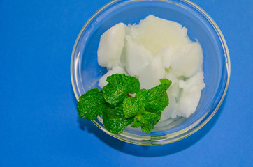 White ice cream sorbet with fresh mint leaves in glass  on blue background, refreshing summer diet dessert, top view copy space.
