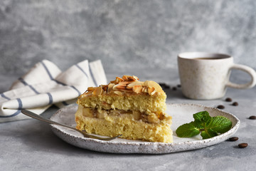 Vanilla cake with butter cream, bananas and almonds on a concrete background.