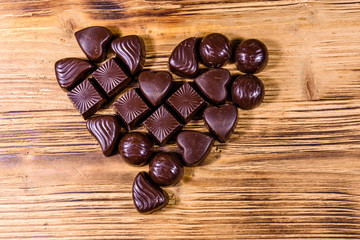 Heap of chocolate candies in shape of heart on a wooden table. Valentine day concept