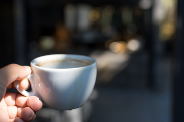Coffee Cup on hand Cafe shop Interior with Blur background