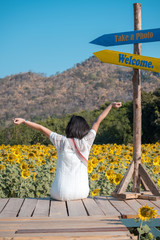 A happy, beautiful young girl sitting in a large field of sunflowers, Summer time