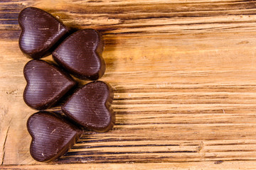 Heap of heart shaped chocolate candies on a wooden table. Top view. Valentine day concept